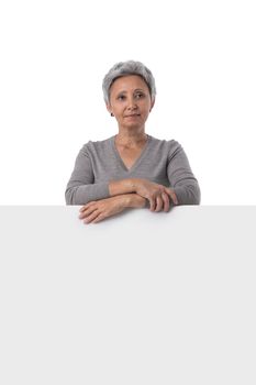 Mature asian woman is holding empty text board over white background and showing thumb up