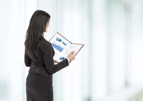 A young, attractive, successful business woman examines graphics at the office