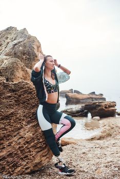After great workout. Young and positive disabled woman in sports clothing adjusting a hood while standing on the beach. Sport concept. Disabled Sportsman. Healthy lifestyle