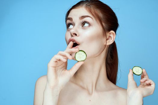 woman with bare shoulders cucumber vitamins health blue background. High quality photo