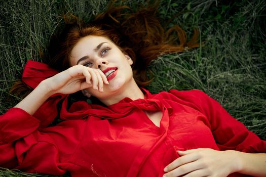 woman in red dress lies on the grass address fashion summer. High quality photo