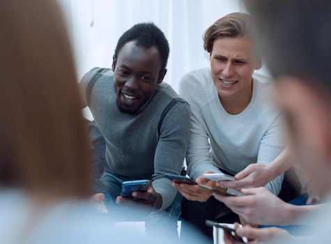 close up. young people with smartphones sitting in a circle. people and technology