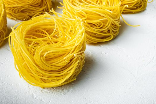 Durum wheat semolina homemade egg pasta tagliarini set, on white stone surface, with copy space for text