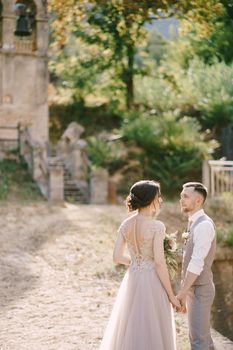 Bride and groom stand against the background of a small chapel. High quality photo