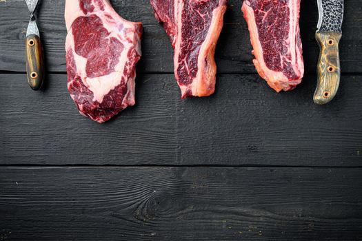 Raw prime beef meat dry aged steak set, tomahawk, t bone or porterhouse and club steak, on black wooden table background, top view flat lay, with copy space for text