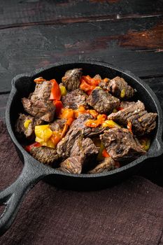 Mongolian beef, pieces of beef stewed in soy sauce set, in cast iron frying pan, on old dark wooden table