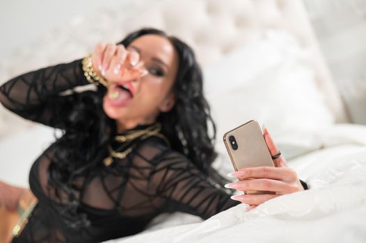 Beautiful caucasian woman is lying on the bed and talking on the phone