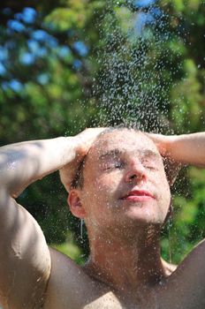 young man relaxing under shower