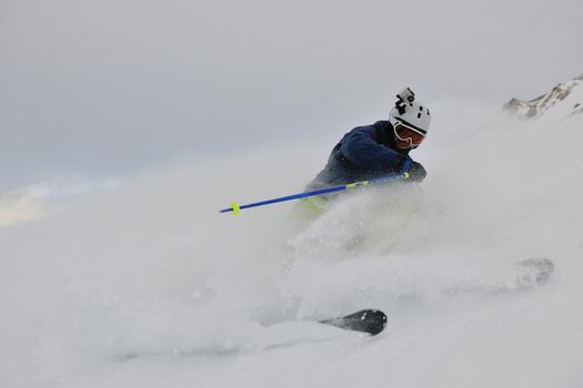 skier skiing downhill on fresh powder snow  with sun and mountains in background