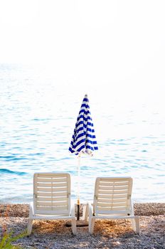 empty chairs on beach with umbrella