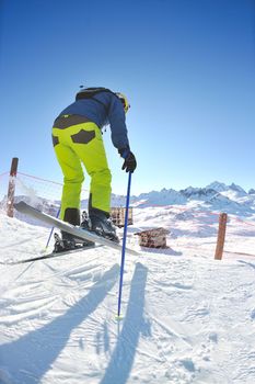 skier skiing downhill on fresh powder snow  with sun and mountains in background