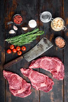 Legendary Ribeye fresh raw beef steak with spices and white beans set, and old butcher cleaver knife, on old dark wooden table background, top view flat lay