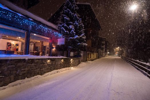 a view on snowy streets of the Alpine mountain village in the cold winter night