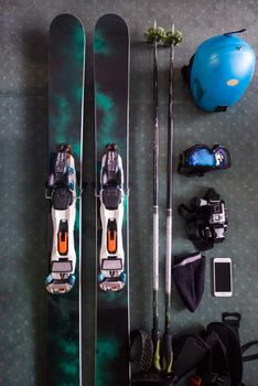 top view of ski accessories placed on floor. Items included helmet, goggles, ski, gloves. Winter sport leisure time concept