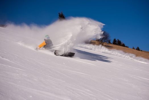 freestyle snowboarder crashes while carving down snowy mountain and leaves a trail of snowflakes behind him