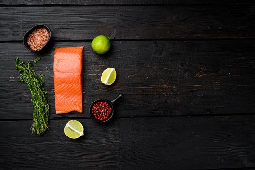 Raw Fillet of salmon set, with herbs, on black wooden table background, top view flat lay, with copy space for text