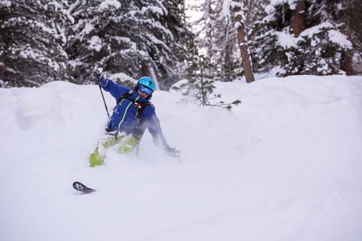 freeride skier with rucksack skiing downhill on fresh powder snow