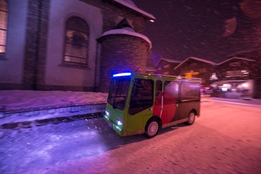 Electric taxi bus on snowy streets in the car-free Alpine mountain village at cold winter night