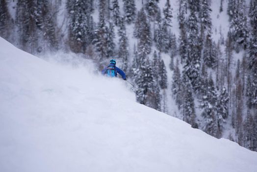 freeride skier with rucksack skiing downhill on fresh powder snow