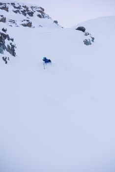 freeride skier with rucksack skiing downhill on fresh powder snow