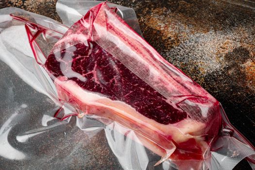 Fresh, huge and appetizing club steak in vacuum packaging set, on old dark rustic background
