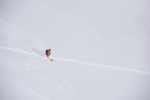 extreme freeride skier skiing on fresh powder snow in downhill at winter mountains