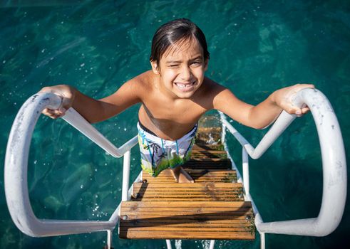 Little child climbing on sea pier