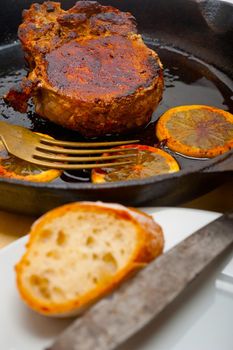 pork chop seared on iron skillet with lemon and spices seasoning