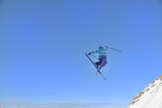 jumping freestyle skier at mountain with fresh snow fresh sunny winter day