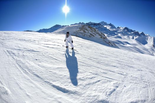 skier skiing downhill on fresh powder snow  with sun and mountains in background