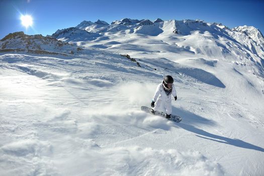 skier skiing downhill on fresh powder snow  with sun and mountains in background