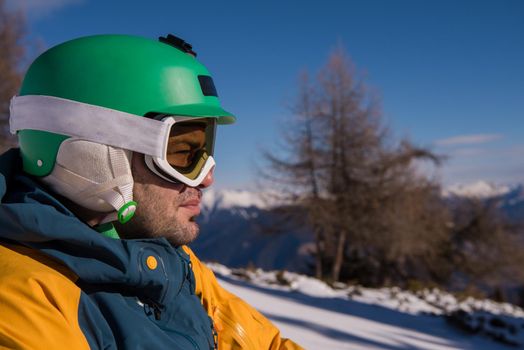 snowboarder relaxing and posing at sunny day on winter season with blue sky in background