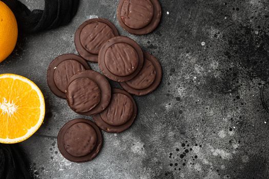 Jaffa Cakes. Cookies covered with dark chocolate and filled with orange marmalade set, on black dark stone table background, top view flat lay, with copy space for text