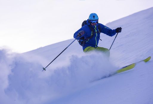 young athlete freestyle Skier having fun while running downhill in beautiful Alpine landscape on sunny day during winter season