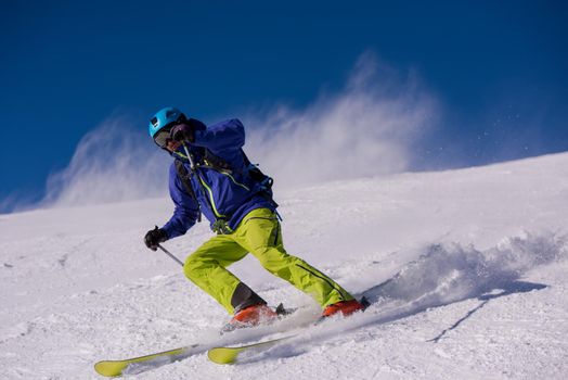 young athlete freestyle Skier having fun while running downhill in beautiful Alpine landscape on sunny day during winter season