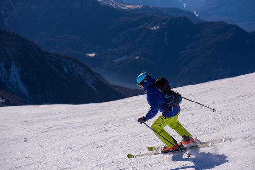 young athlete freestyle Skier having fun while running downhill in beautiful Alpine landscape on sunny day during winter season