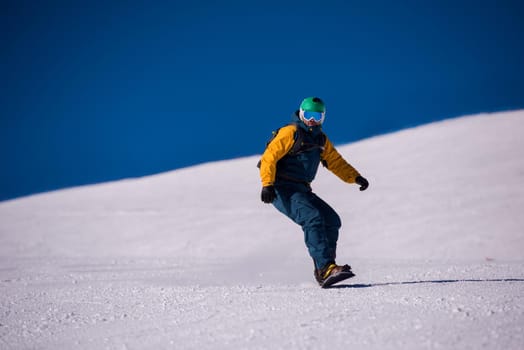 Young freestyle snowboarder running down the slope and ride free style at sunny winter day on Alpine mountains. Winter sport and recreation, leisure outdoor activities.