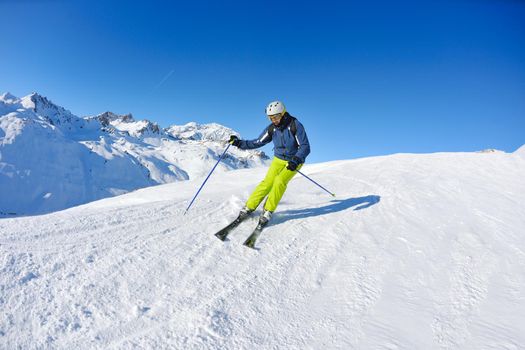 skier skiing downhill on fresh powder snow  with sun and mountains in background