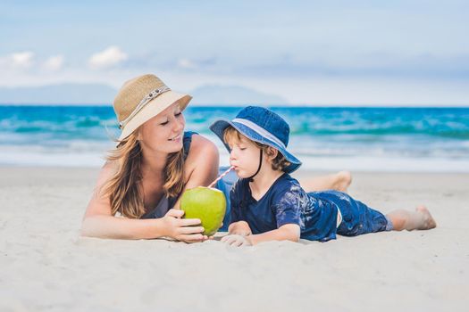 Mom and son enjoy the beach and drink coconut.