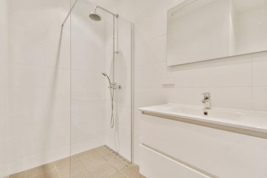 Bathroom interior with hanging chest of drawers and shower cubicle with glass partition