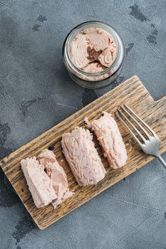 Canned tuna fillet meat in olive oil, on gray background, flat lay