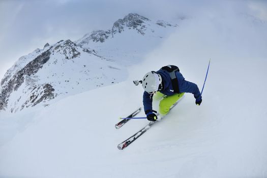 skier skiing downhill on fresh powder snow  with sun and mountains in background