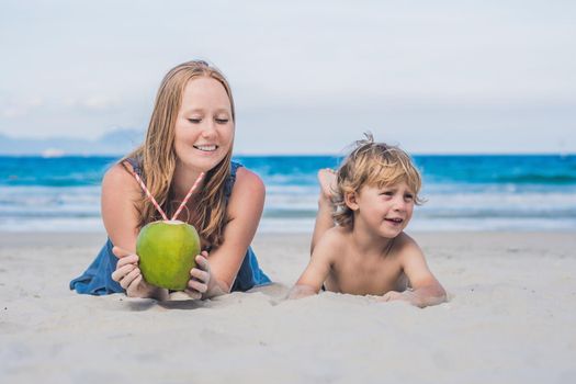 Mom and son enjoy the beach and drink coconut.