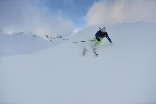 skier skiing downhill on fresh powder snow  with sun and mountains in background