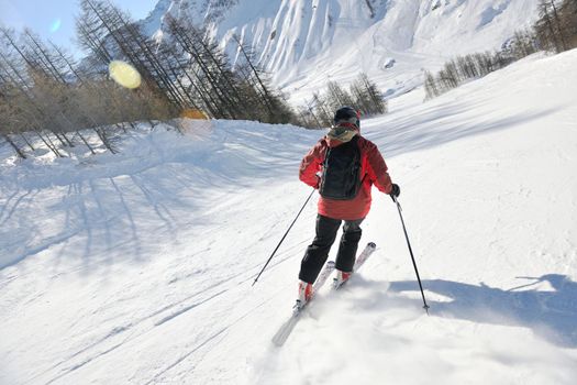 skier skiing downhill on fresh powder snow  with sun and mountains in background