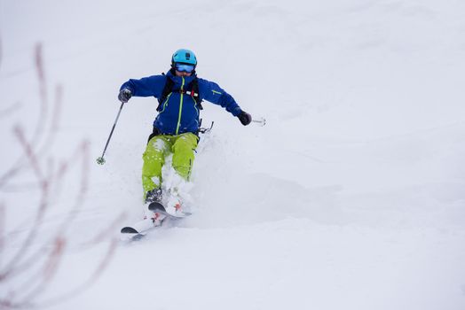freeride skier with rucksack skiing downhill on fresh powder snow