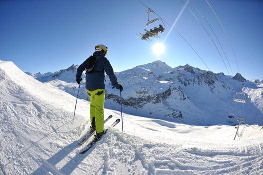 skier skiing downhill on fresh powder snow  with sun and mountains in background