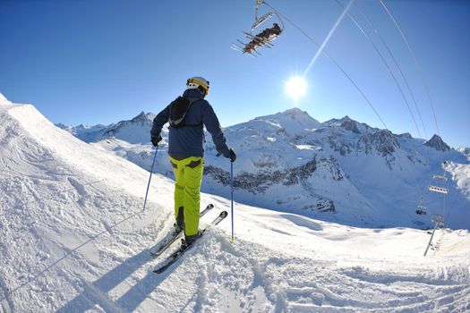 skier skiing downhill on fresh powder snow  with sun and mountains in background