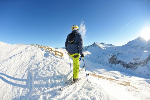 skier skiing downhill on fresh powder snow  with sun and mountains in background