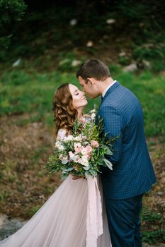 Bride with a bouquet almost kisses the groom in the garden. High quality photo